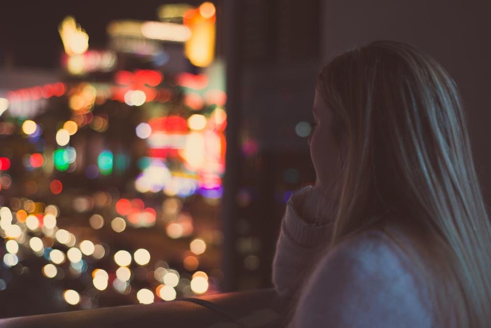 Mulher pensativa olhando pela janela, refletindo sobre dependência emocional
