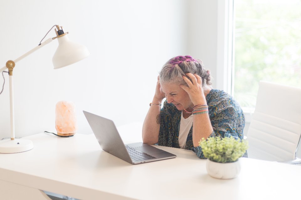 Mulher trabalhando em sua mesa, refletindo sobre procrastinação